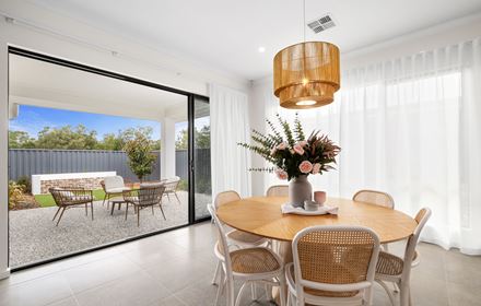 The dining space in The Dallas Platinum display home by Home Group opening up to the outdoor alfresco area