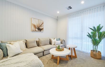 The theatre room in The Mahala display home by Blueprint Homes featuring wall length couch and white wall paneling